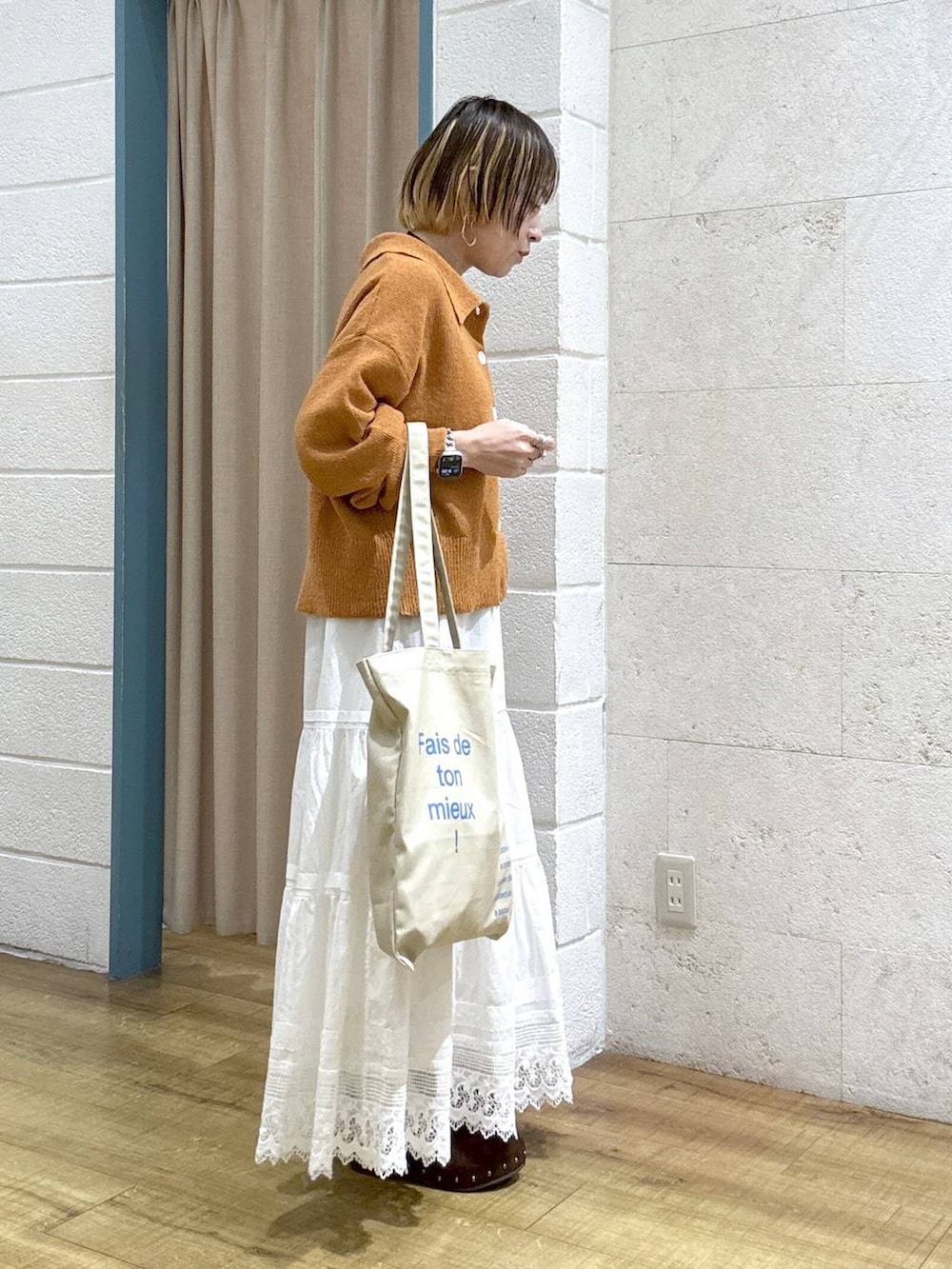 ベージュ系のトートバッグ、ブラウン系のサンダル、オレンジ系のカーディガン/ボレロを着用したレディースの春コーディネートの5枚目の写真
