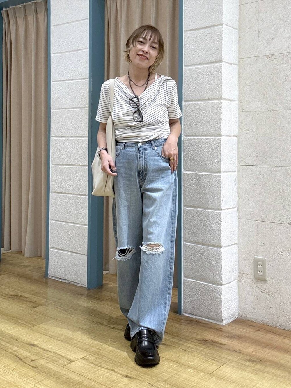 ブルー系のデニムパンツ、ブラック系のローファー、ホワイト系のショルダーバッグを着用したレディースの春コーディネートの6枚目の写真