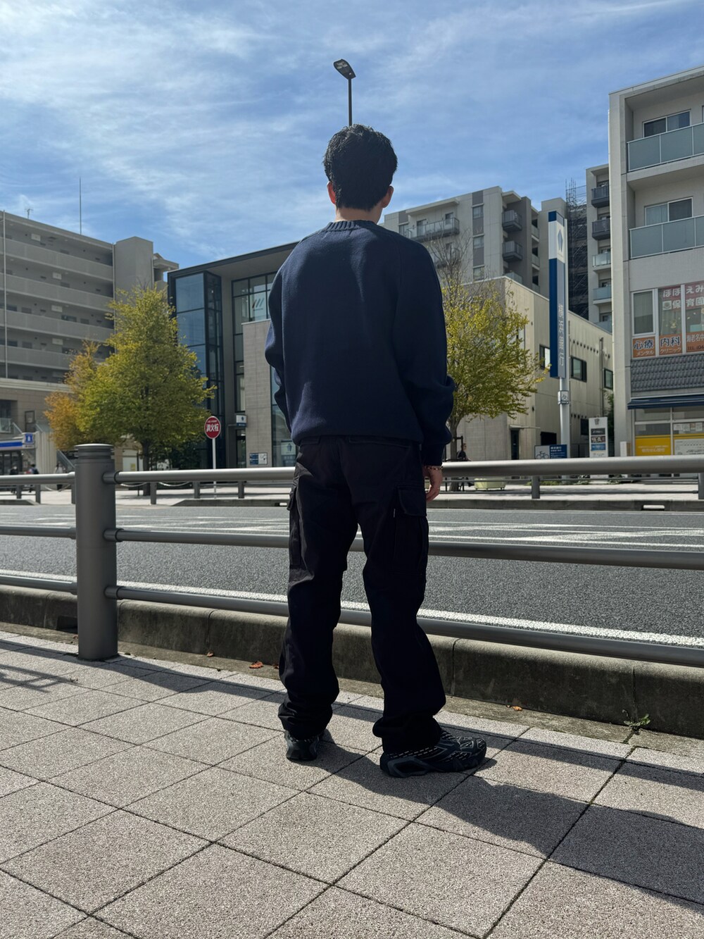 ブルー系のニット/セーター、ブラック系のカーゴパンツ、ブラック系のベルトを着用したメンズの冬コーディネートの2枚目の写真