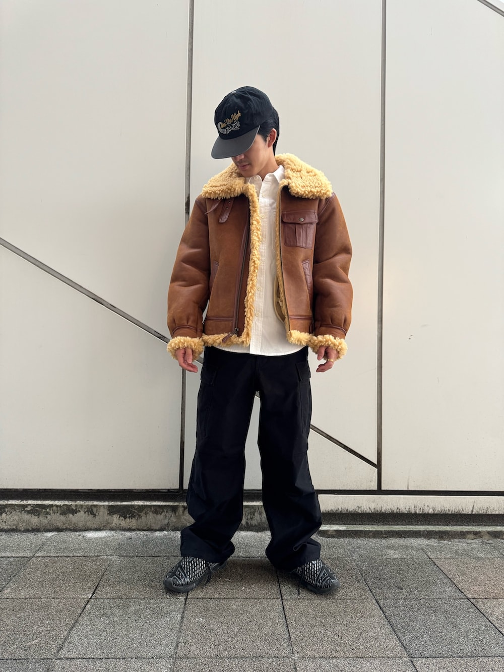 ブラウン系のムートンコート、ブラック系のカーゴパンツ、ホワイト系のシャツ/ブラウスを着用したメンズの冬コーディネートの3枚目の写真