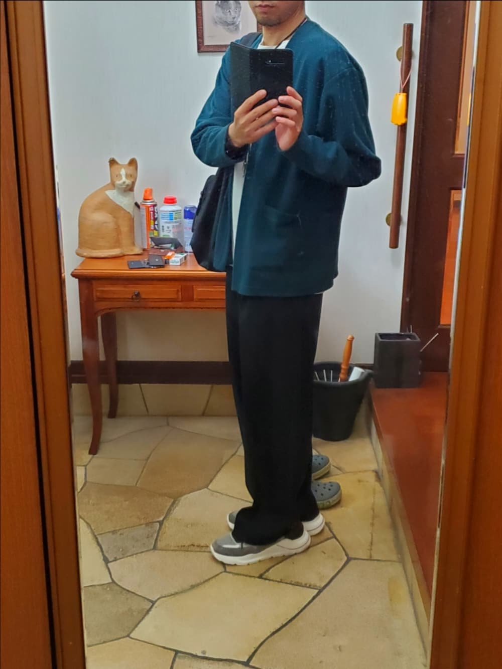 グリーン系のカーディガン/ボレロ、ホワイト系のTシャツ/カットソー、ブラック系のスラックスを着用したメンズの秋コーディネートの2枚目の写真