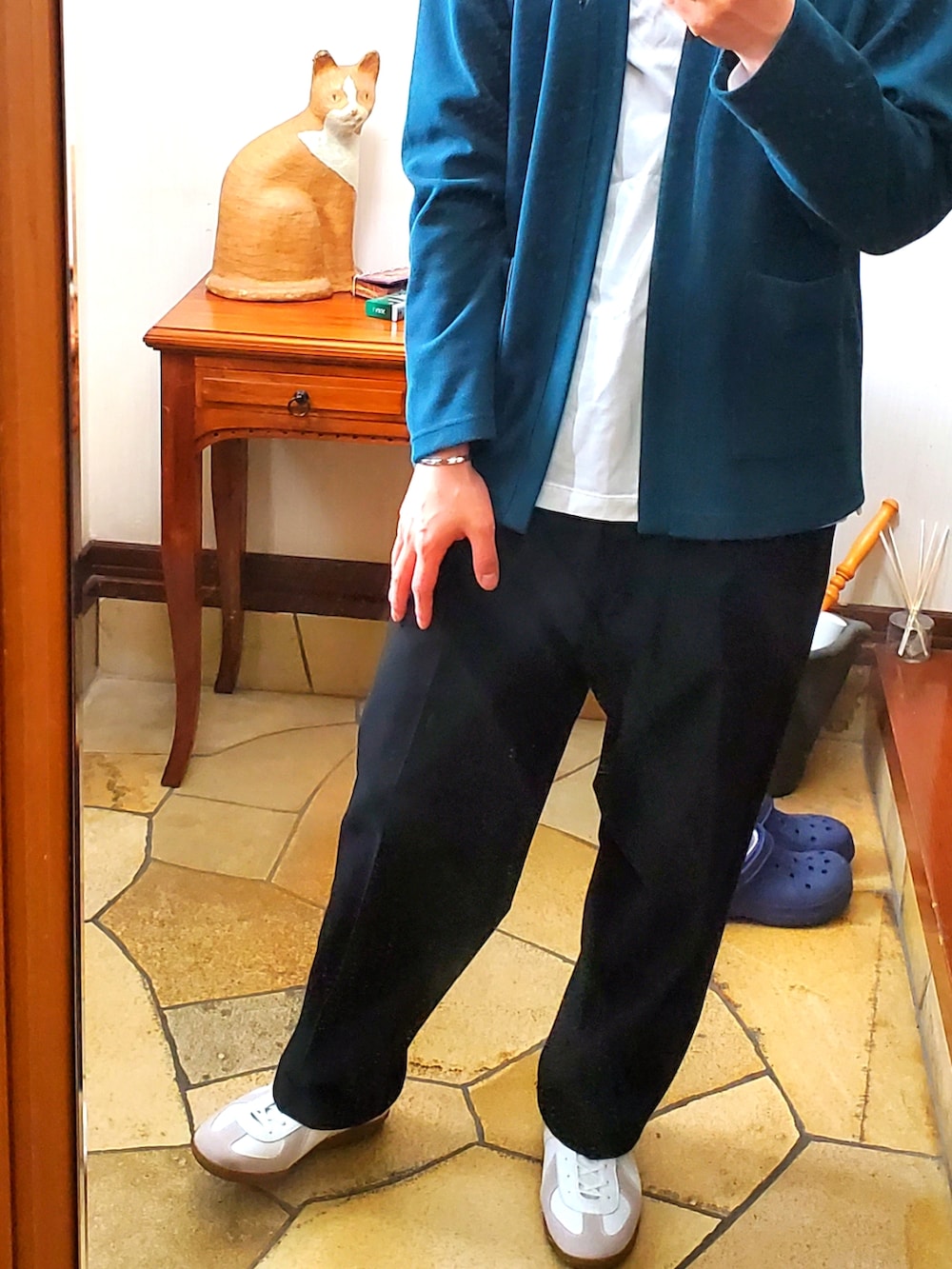 グリーン系のカーディガン/ボレロ、ホワイト系のTシャツ/カットソー、ブラック系のスラックスを着用したメンズの春コーディネートの3枚目の写真