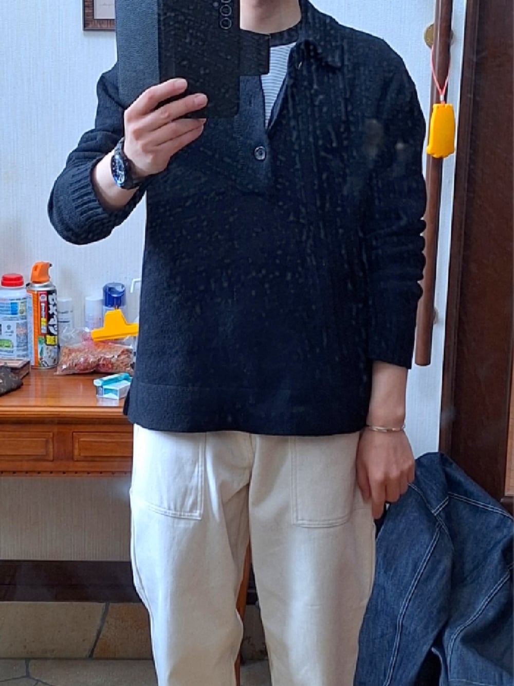 ブルー系のデニムジャケット、ブラック系のニット/セーター、ホワイト系のデニムパンツを着用したメンズの春コーディネートの2枚目の写真