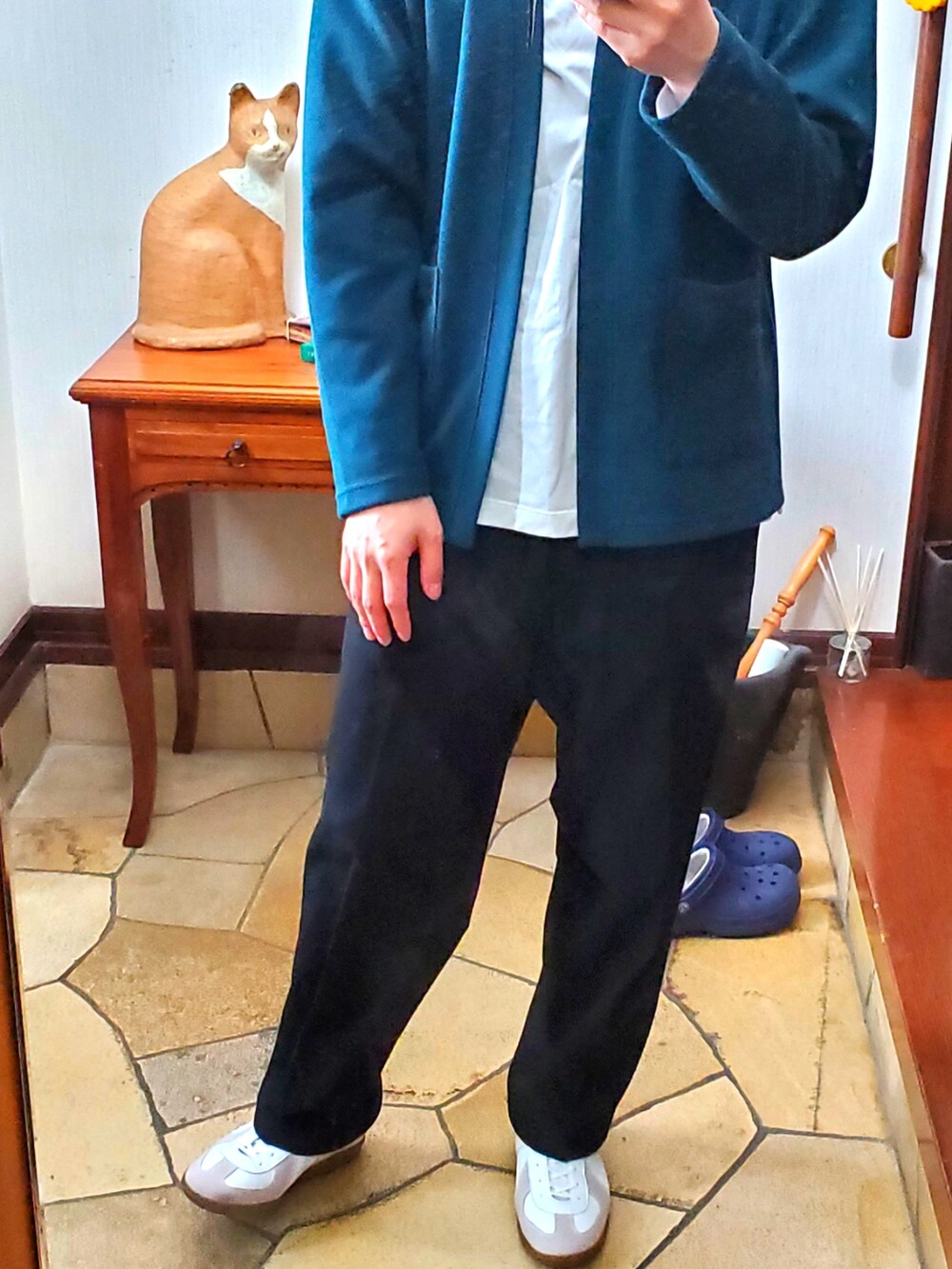 グリーン系のカーディガン/ボレロ、ホワイト系のTシャツ/カットソー、ブラック系のスラックスを着用したメンズの春コーディネートの2枚目の写真