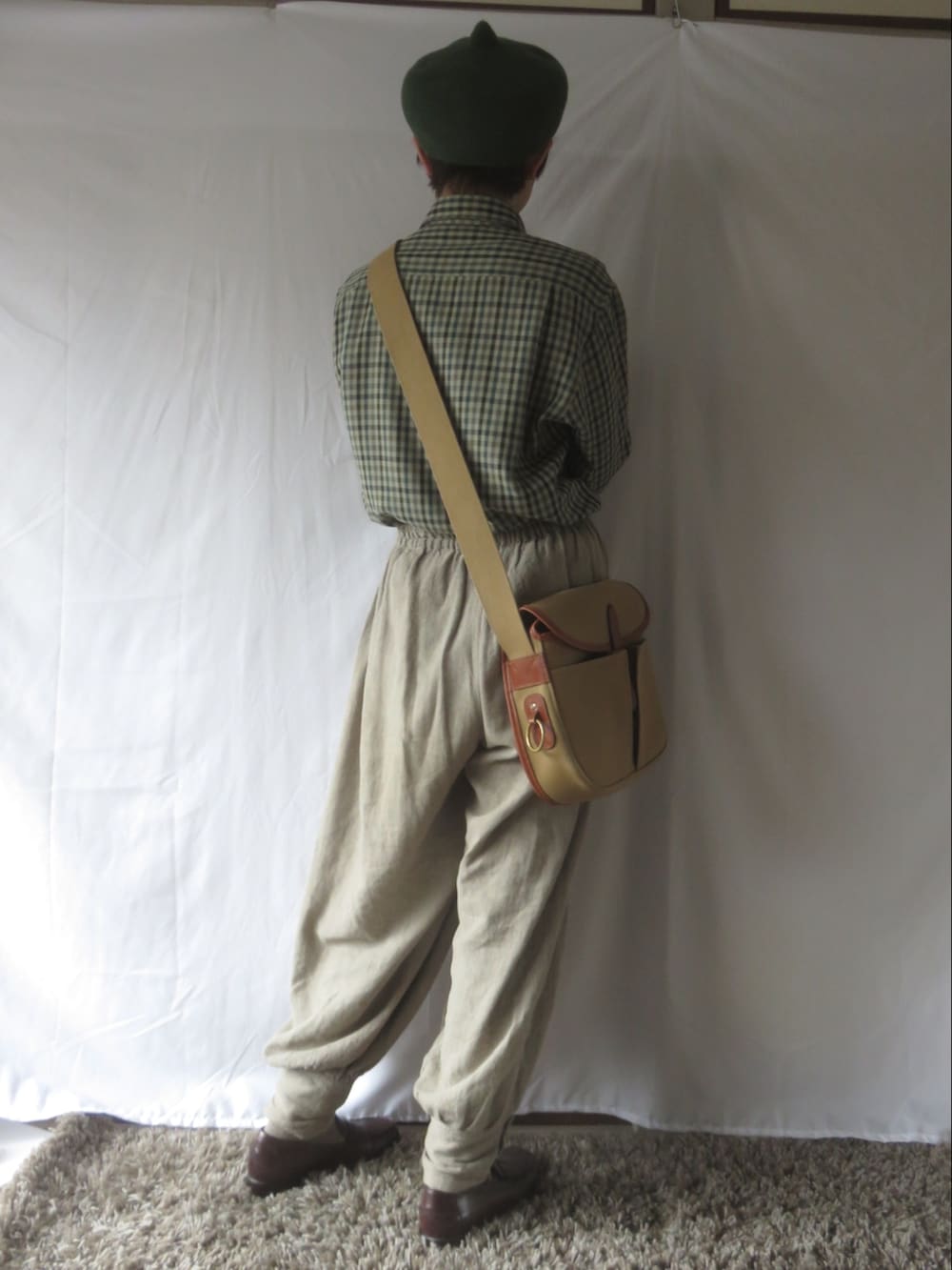 グレー系のパンツ、ブラウン系のローファー、ベージュ系のショルダーバッグを着用したレディースの春コーディネートの2枚目の写真