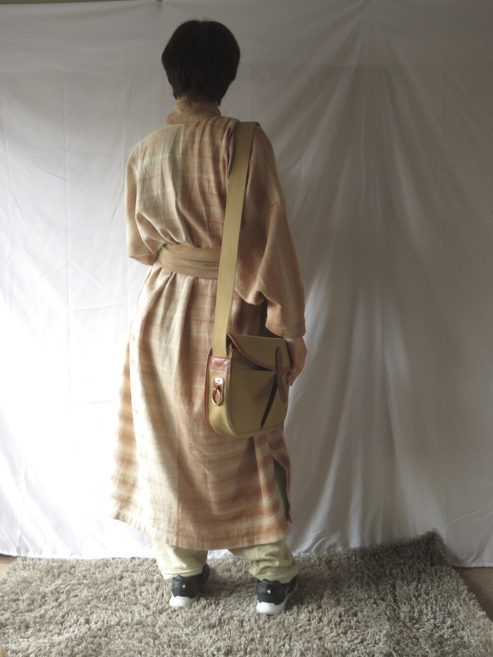 ピンク系のワンピース、ブラック系のスニーカー、ピンク系のストール/ショールを着用したレディースの春コーディネートの2枚目の写真