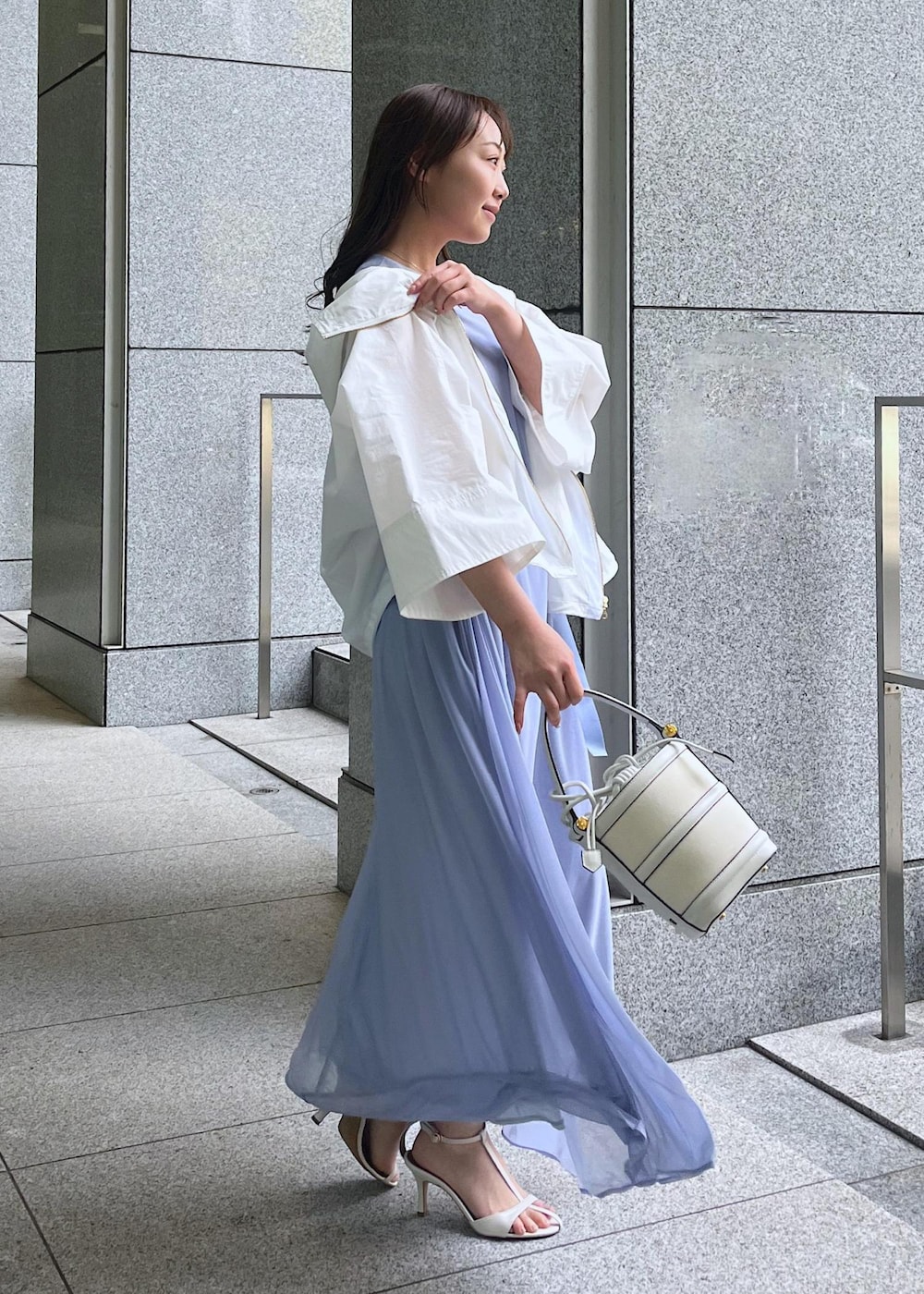 ホワイト系のハンドバッグ、ホワイト系のサンダル、ホワイト系のマウンテンパーカーを着用したレディースの春コーディネートの2枚目の写真