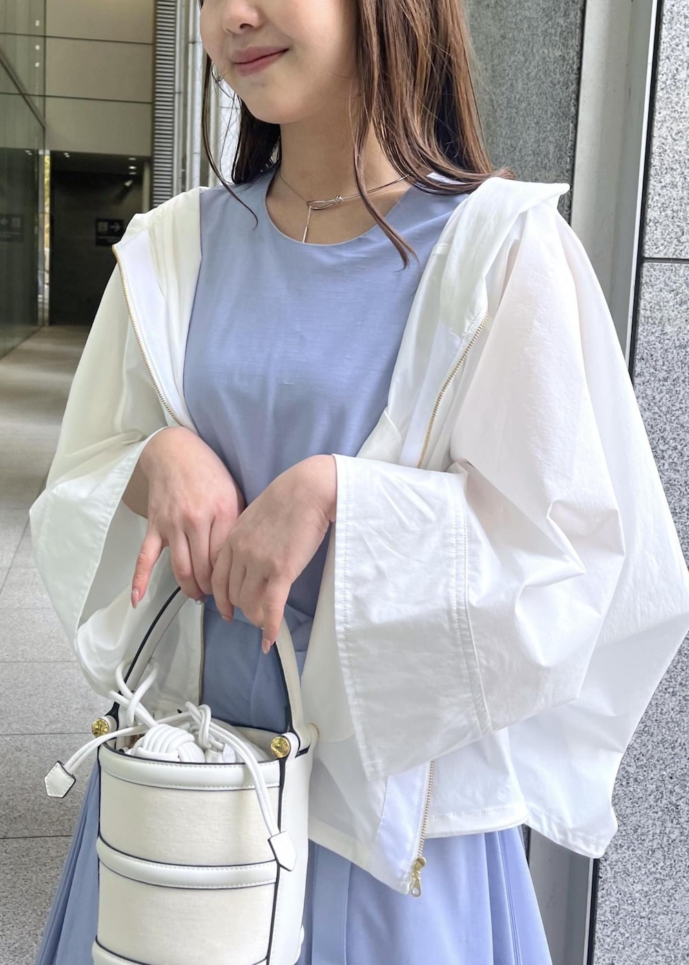 ホワイト系のハンドバッグ、ホワイト系のサンダル、ホワイト系のマウンテンパーカーを着用したレディースの春コーディネートの7枚目の写真