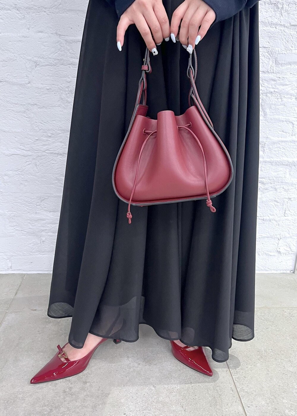 レッド系のパンプス、レッド系のハンドバッグ、ブラック系のスカートを着用したレディースの秋コーディネートの9枚目の写真