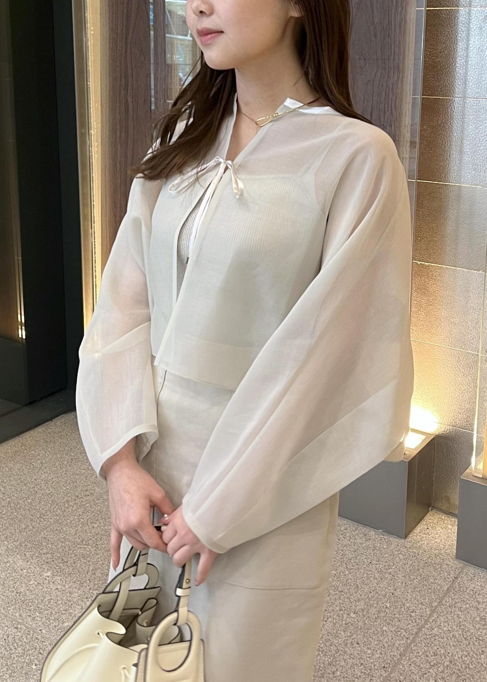 ホワイト系のハンドバッグ、シルバー系のサンダル、ベージュ系のスカートを着用したレディースの春コーディネートの8枚目の写真