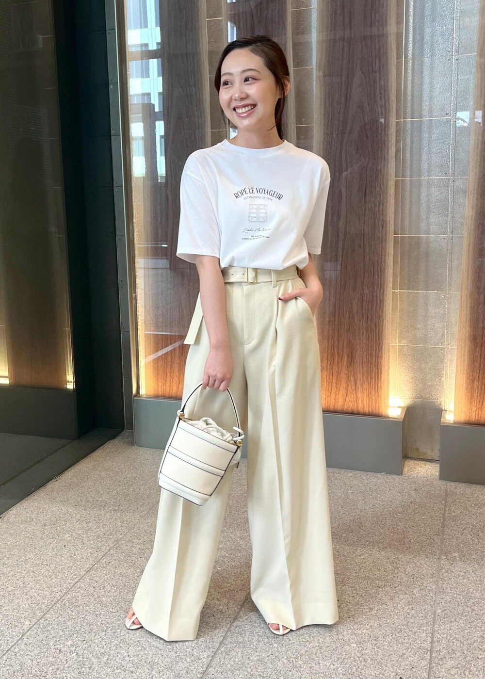 ホワイト系のハンドバッグ、ホワイト系のサンダル、ホワイト系のTシャツ/カットソーを着用したレディースの春コーディネートの2枚目の写真