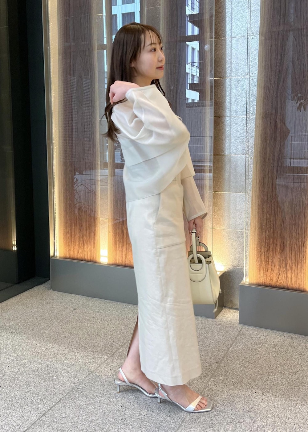 ホワイト系のハンドバッグ、シルバー系のサンダル、ベージュ系のスカートを着用したレディースの春コーディネートの3枚目の写真