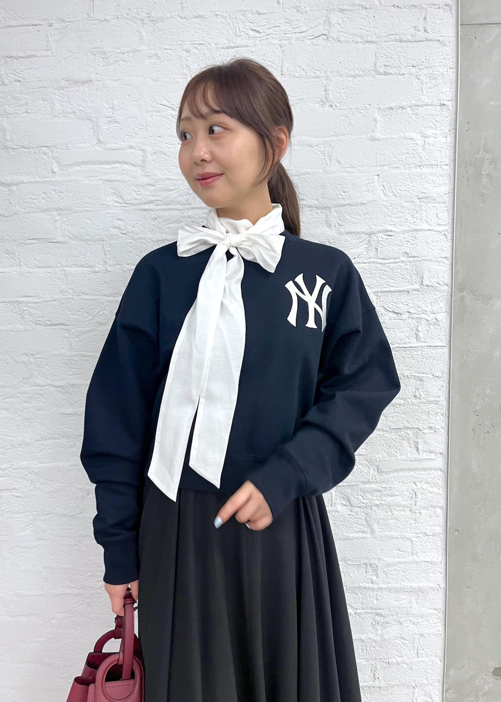 レッド系のパンプス、レッド系のハンドバッグ、ブラック系のスカートを着用したレディースの秋コーディネートの8枚目の写真