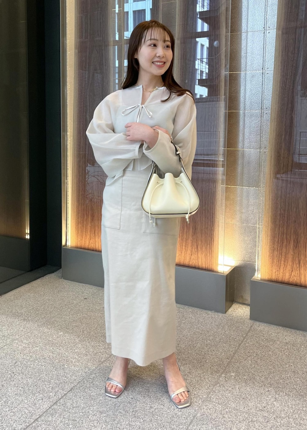 ホワイト系のハンドバッグ、シルバー系のサンダル、ベージュ系のスカートを着用したレディースの春コーディネートの7枚目の写真
