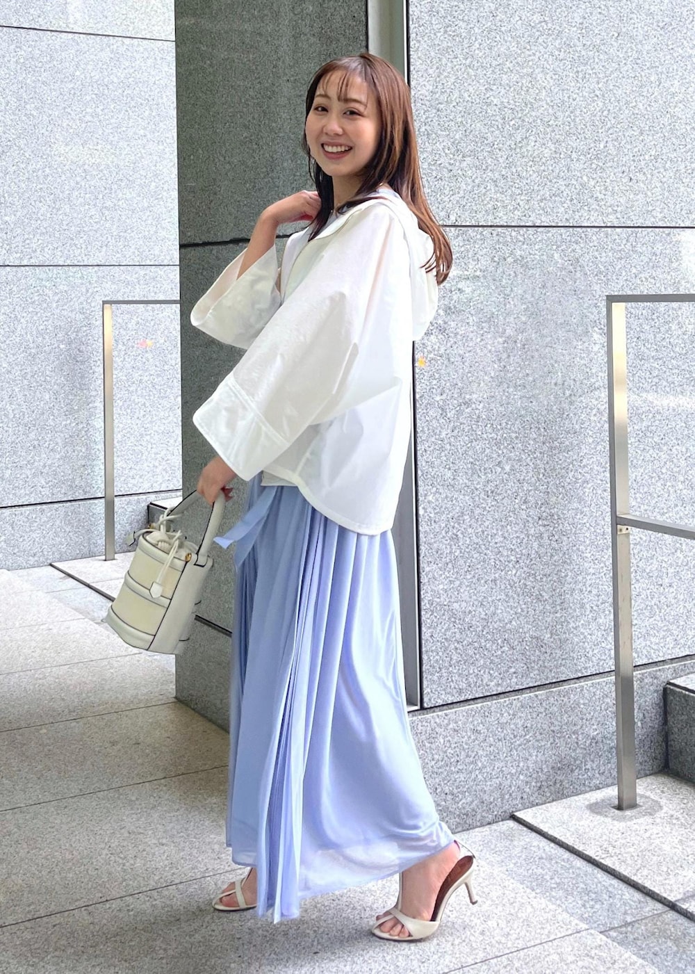 ホワイト系のハンドバッグ、ホワイト系のサンダル、ホワイト系のマウンテンパーカーを着用したレディースの春コーディネートの3枚目の写真