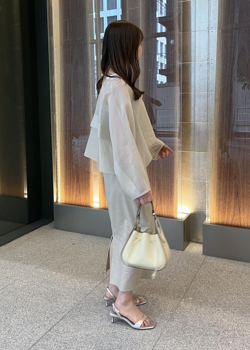 ホワイト系のハンドバッグ、シルバー系のサンダル、ベージュ系のスカートを着用したレディースの春コーディネートの5枚目の写真