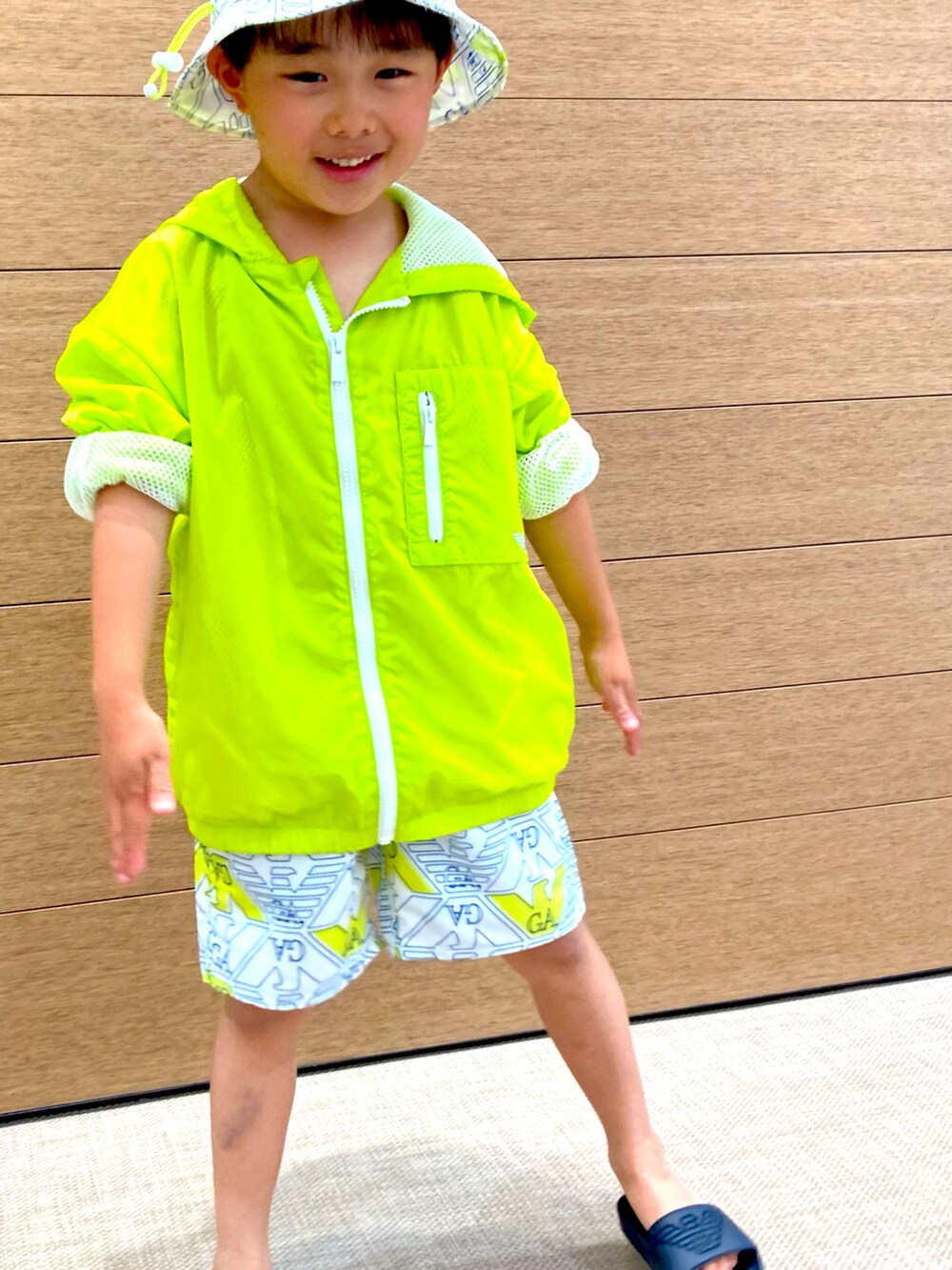 イエロー系のブルゾン、ホワイト系のスウェットパンツ、ホワイト系のハットを着用したキッズの春コーディネートの2枚目の写真