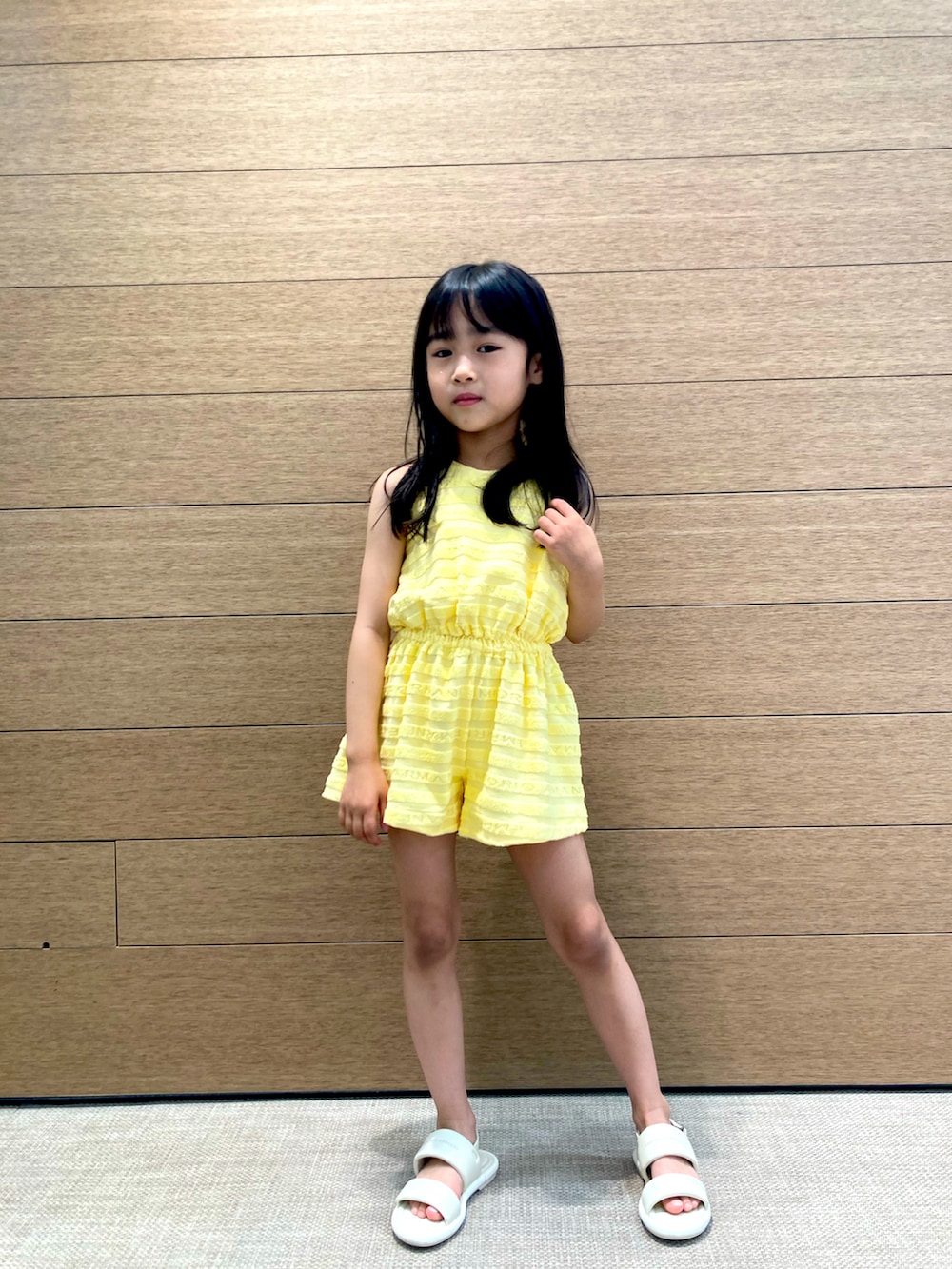 ホワイト系のサンダル、イエロー系のオールインワン・サロペットを着用したキッズの春コーディネートの2枚目の写真