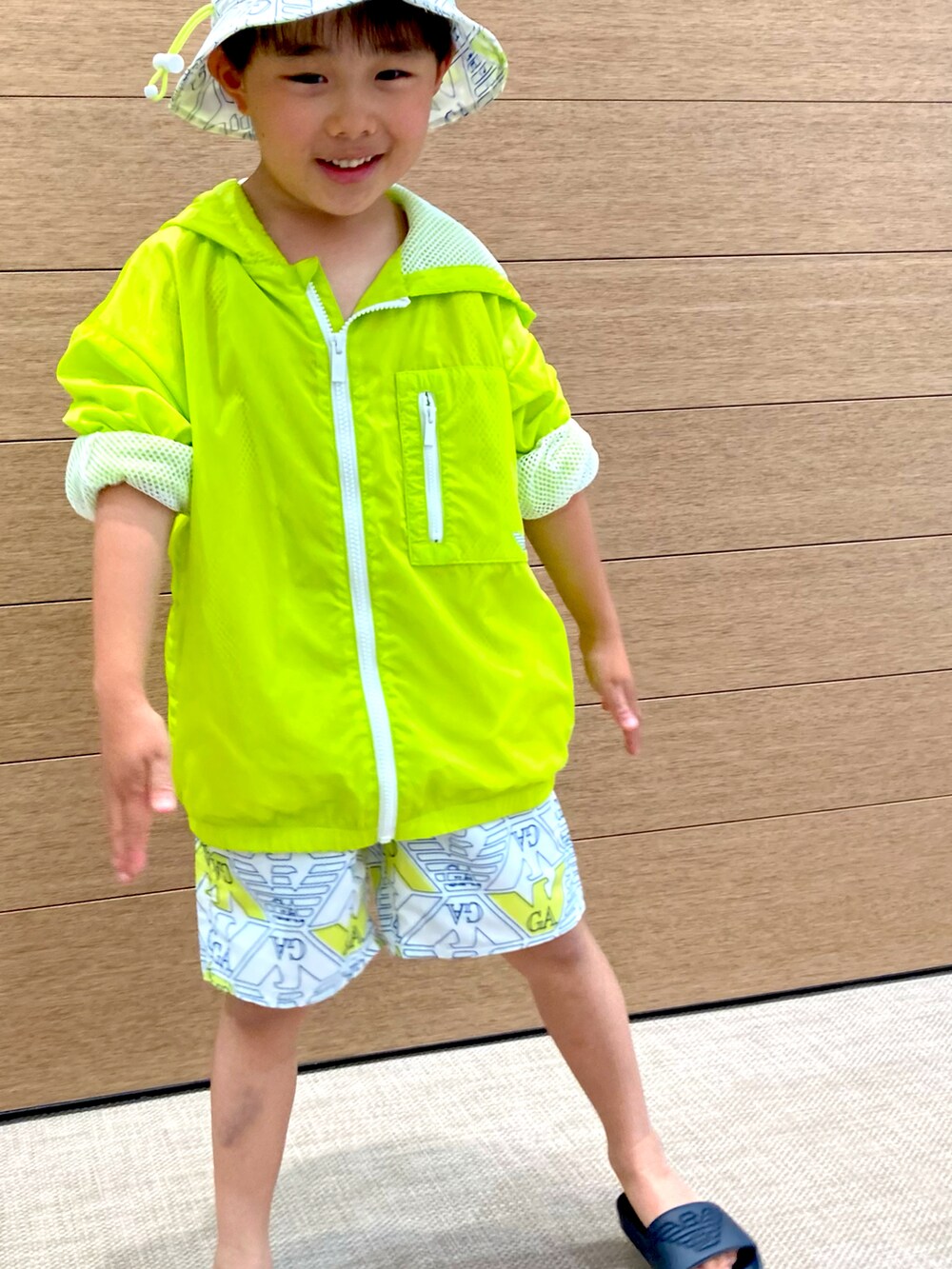 イエロー系のブルゾン、イエロー系のスウェットパンツ、ブラック系のサンダルを着用したキッズの春コーディネートの2枚目の写真