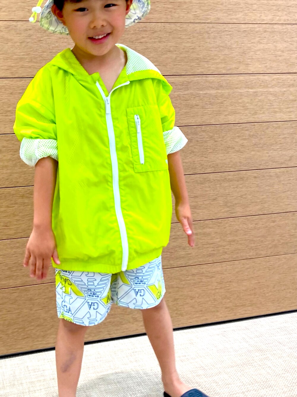 イエロー系のブルゾン、ホワイト系のスウェットパンツ、ホワイト系のハットを着用したキッズの春コーディネートの3枚目の写真