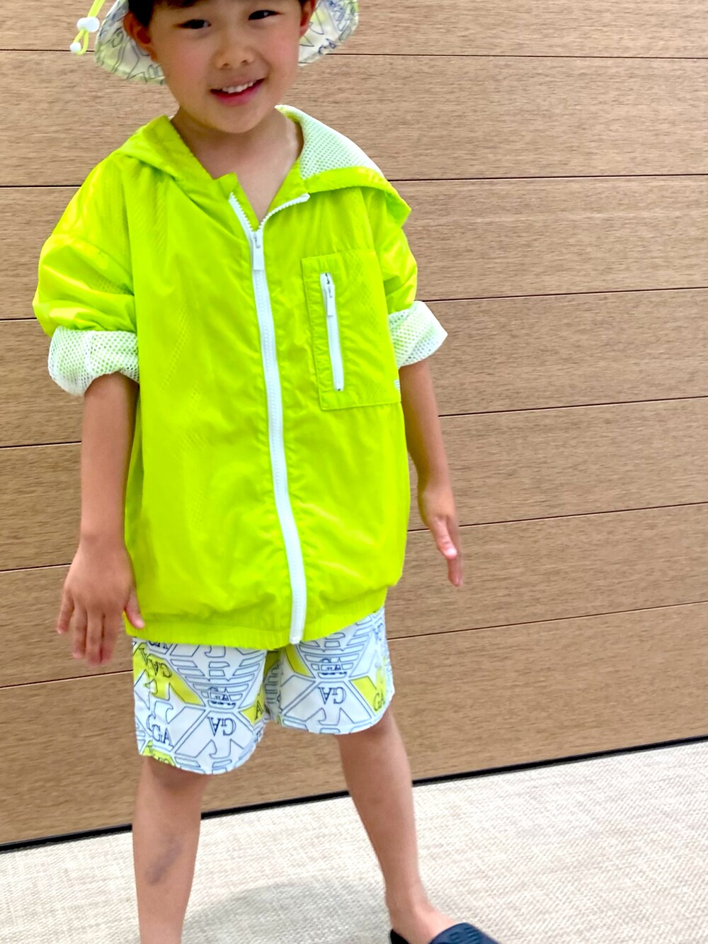 イエロー系のブルゾン、イエロー系のスウェットパンツ、ブラック系のサンダルを着用したキッズの春コーディネートの3枚目の写真