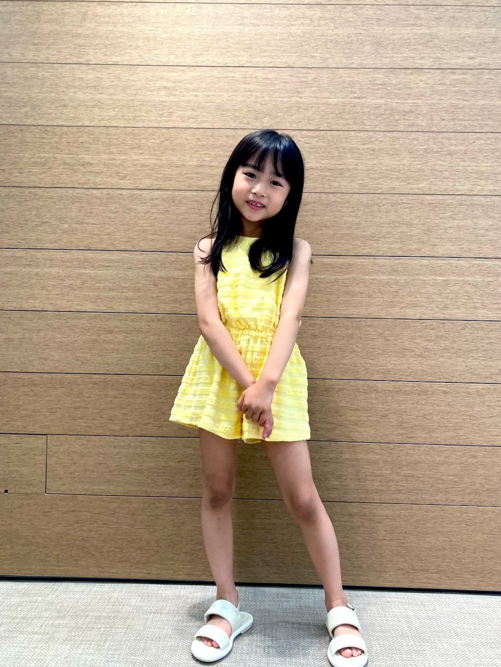 ホワイト系のサンダル、イエロー系のオールインワン・サロペットを着用したキッズの春コーディネートの4枚目の写真