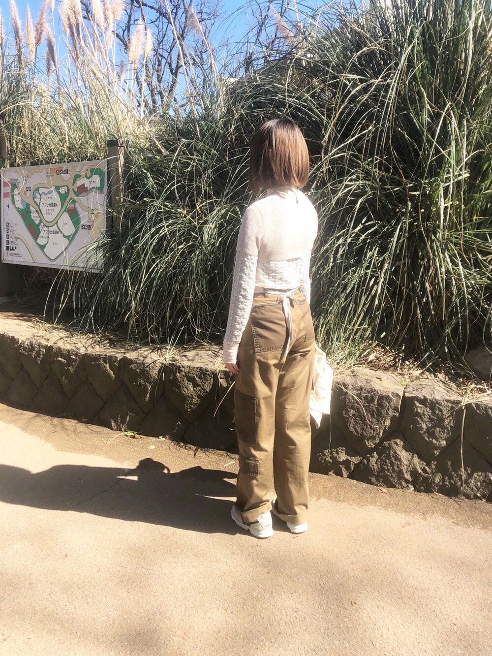 ホワイト系のTシャツ/カットソー、ホワイト系のスニーカー、ベージュ系のニット/セーターを着用したレディースの春コーディネートの2枚目の写真