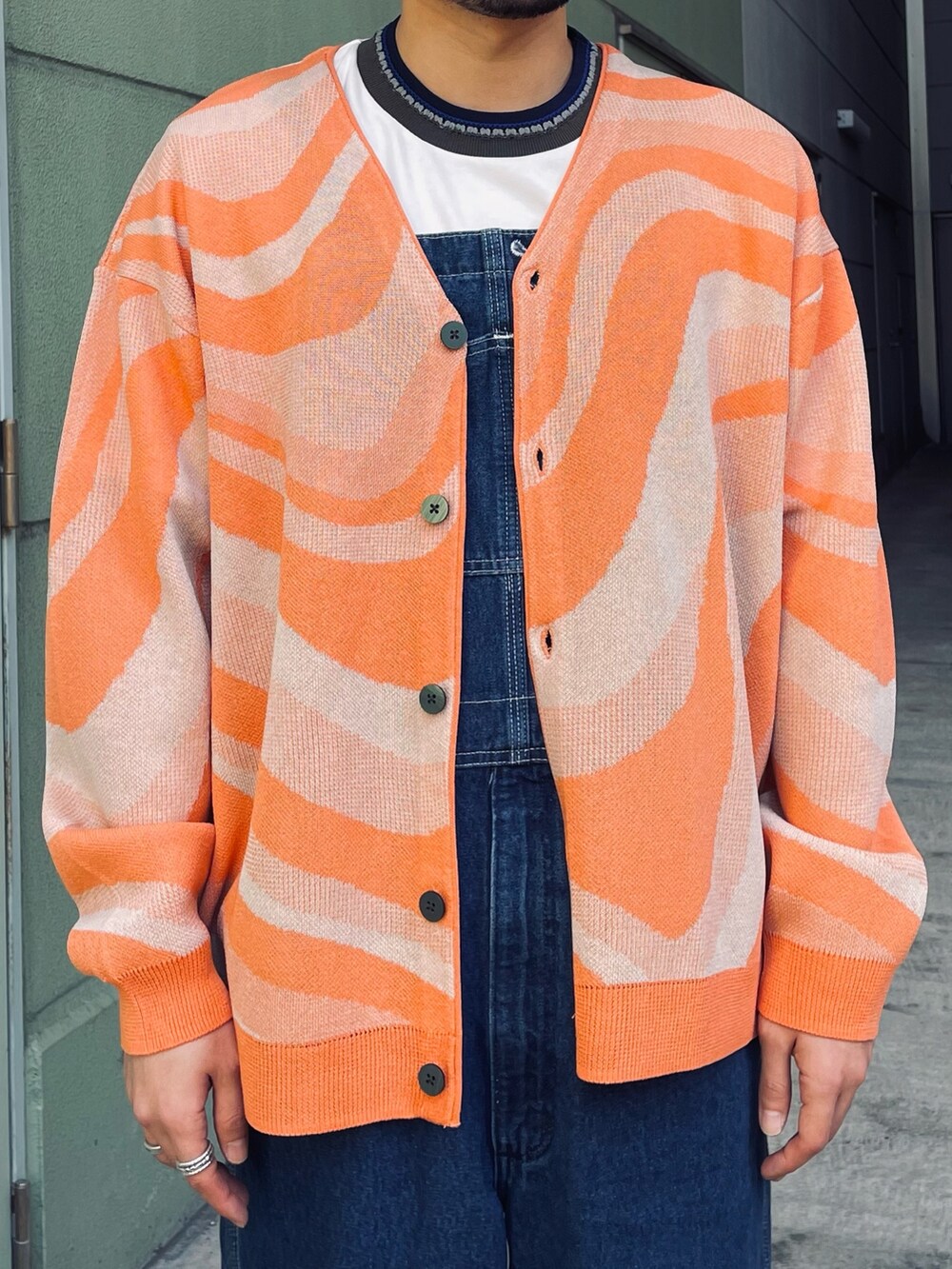 オレンジ系のカーディガン/ボレロ、ホワイト系のTシャツ/カットソー、ブラック系のスニーカーを着用したメンズの春コーディネートの2枚目の写真