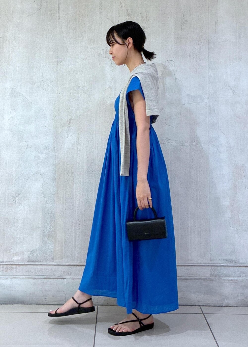 グレー系のカーディガン/ボレロ、ブラック系のサンダルを着用したレディースの春コーディネートの2枚目の写真