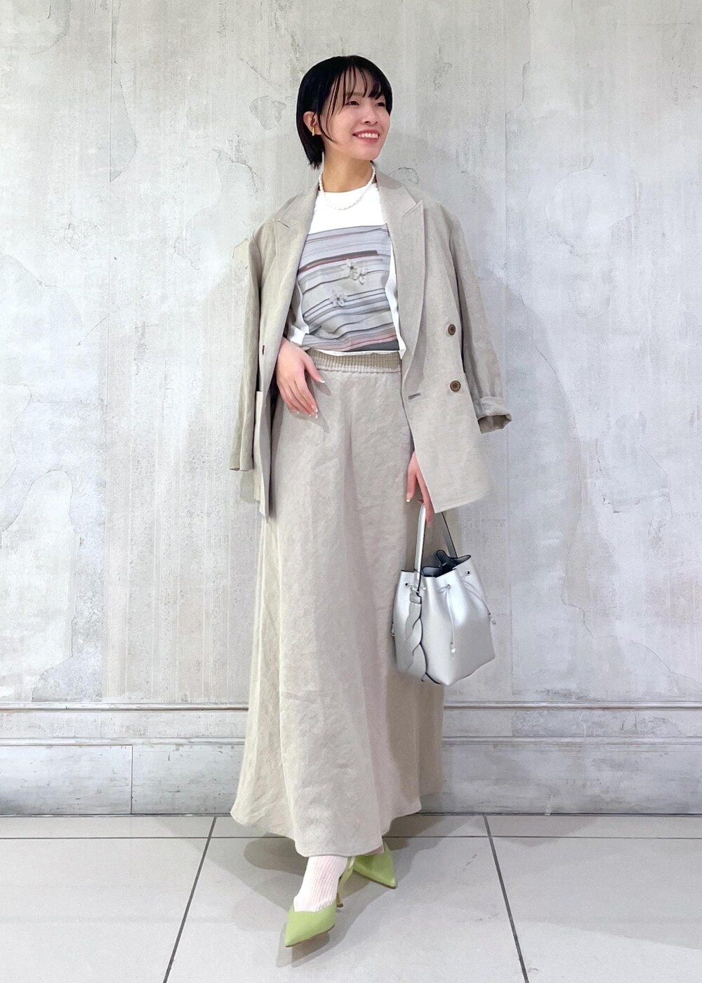 ベージュ系のテーラードジャケット、ベージュ系のスカート、ホワイト系のTシャツ/カットソーを着用したレディースの冬コーディネートの4枚目の写真