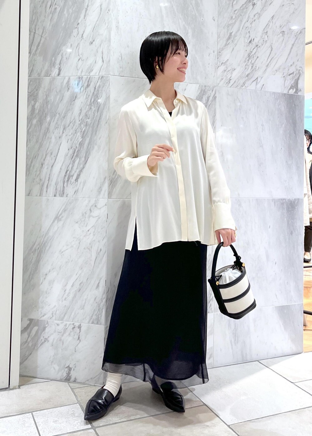 ブラック系のハンドバッグ、ブラック系のパンプス、ホワイト系のシャツ/ブラウスを着用したレディースの春コーディネートの4枚目の写真