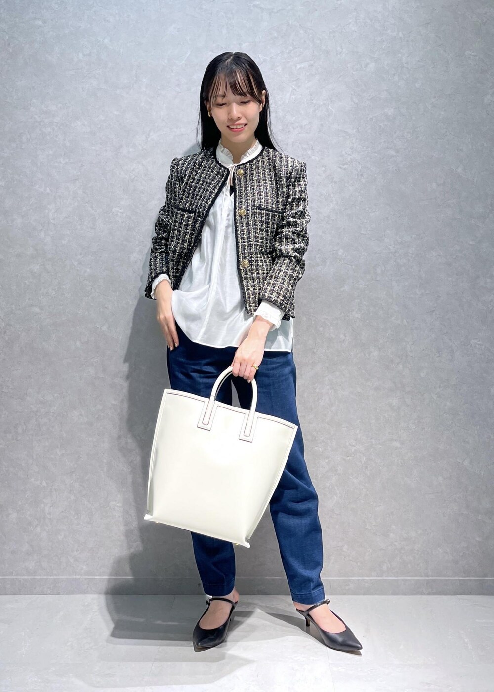 ブラック系のパンプス、ホワイト系のトートバッグ、ブルー系のデニムパンツを着用したレディースの秋コーディネートの4枚目の写真