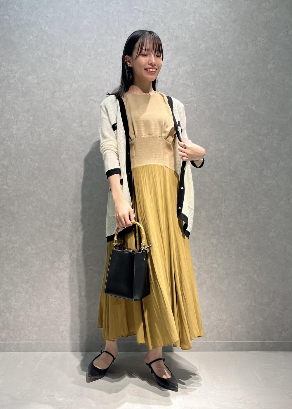 ブラック系のパンプス、ブラック系のハンドバッグ、ホワイト系のカーディガン/ボレロを着用したレディースの夏コーディネートの4枚目の写真
