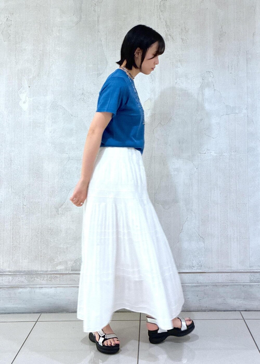 ホワイト系のスカート、ブラック系のトートバッグ、ブルー系のTシャツ/カットソーを着用したレディースの夏コーディネートの4枚目の写真