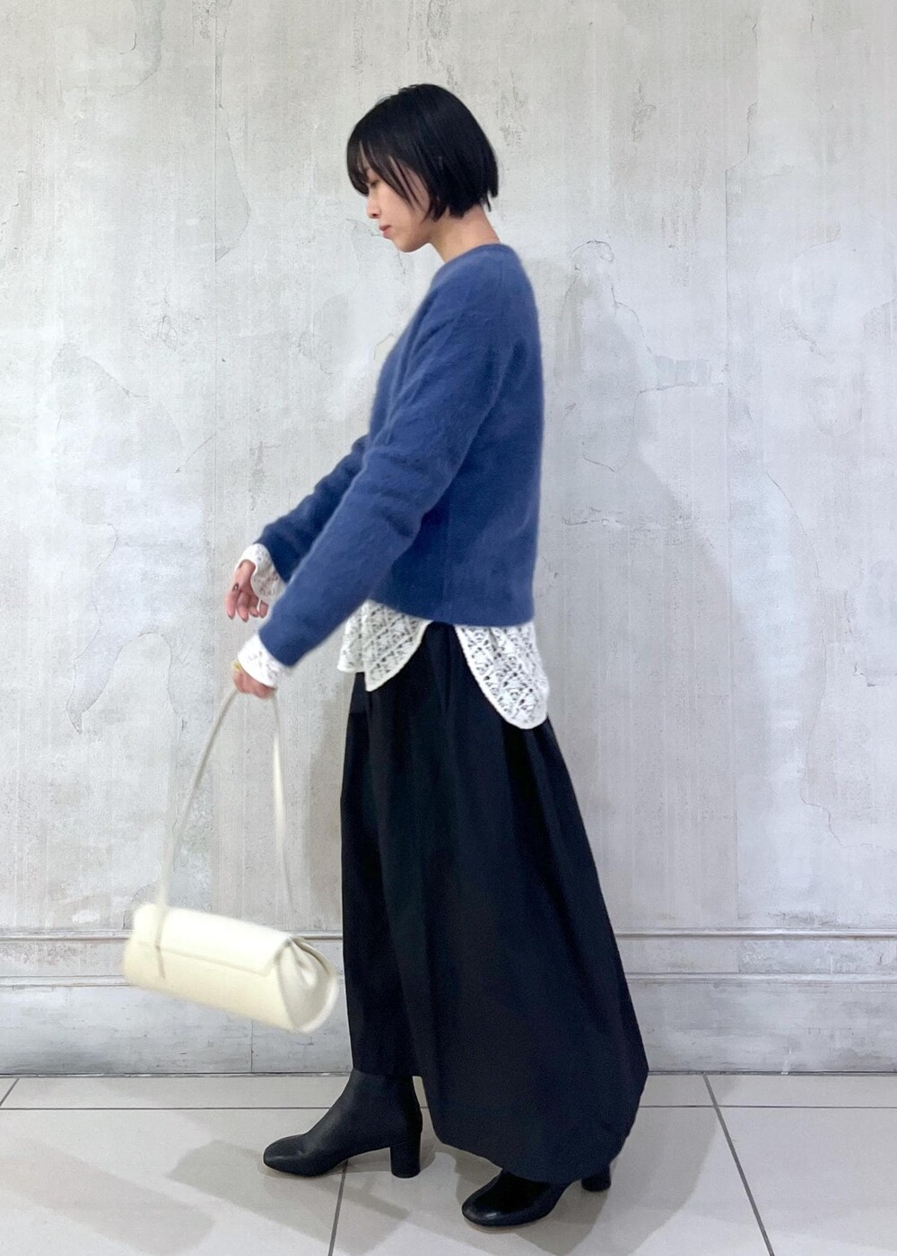 ホワイト系のショルダーバッグ、ブラック系のスカート、ホワイト系のTシャツ/カットソーを着用したレディースの冬コーディネートの4枚目の写真