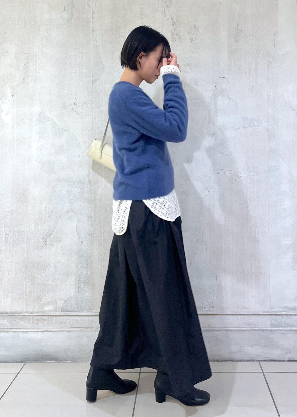 ホワイト系のショルダーバッグ、ブラック系のスカート、ホワイト系のTシャツ/カットソーを着用したレディースの冬コーディネートの2枚目の写真