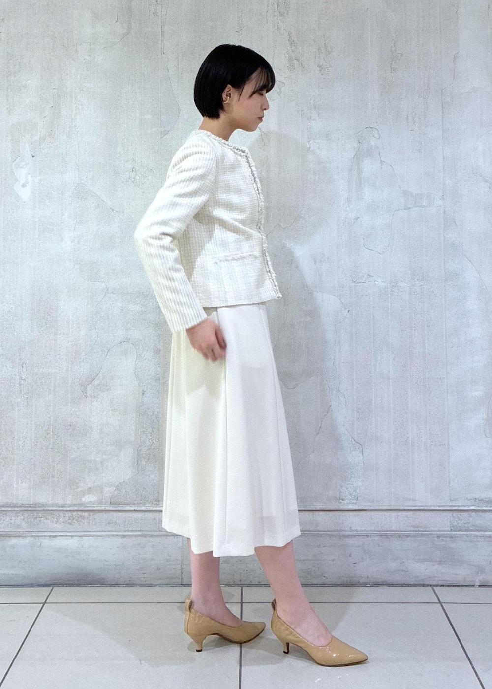 ベージュ系のワンピース、ホワイト系のノーカラージャケット、ホワイト系のハンドバッグを着用したレディースの冬コーディネートの5枚目の写真