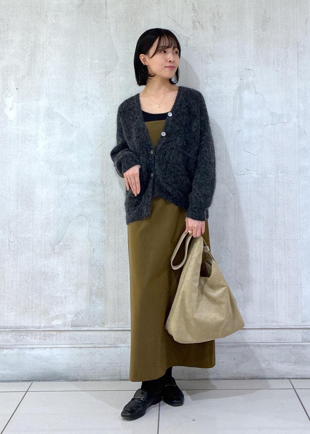 グレー系のカーディガン/ボレロ、ブラウン系のワンピース、ベージュ系のショルダーバッグを着用したレディースの冬コーディネートの2枚目の写真
