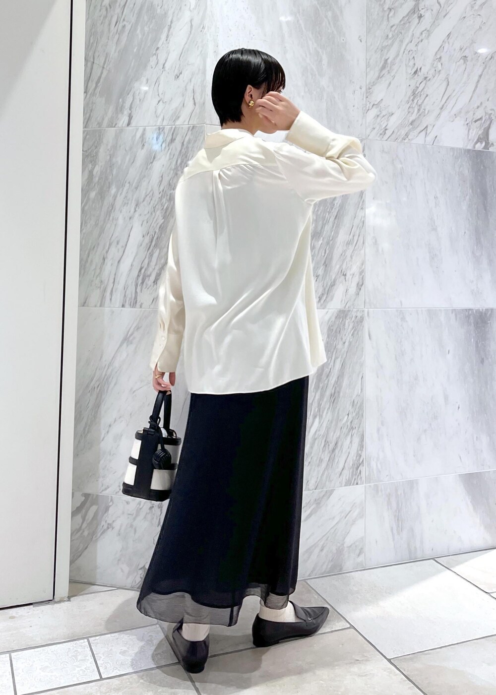ブラック系のハンドバッグ、ブラック系のパンプス、ホワイト系のシャツ/ブラウスを着用したレディースの春コーディネートの3枚目の写真