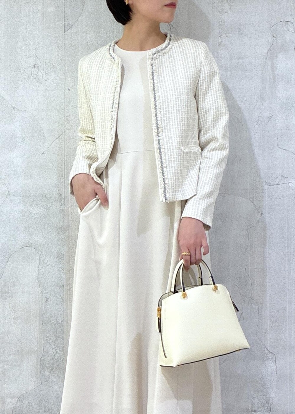 ベージュ系のワンピース、ホワイト系のノーカラージャケット、ホワイト系のハンドバッグを着用したレディースの冬コーディネートの6枚目の写真