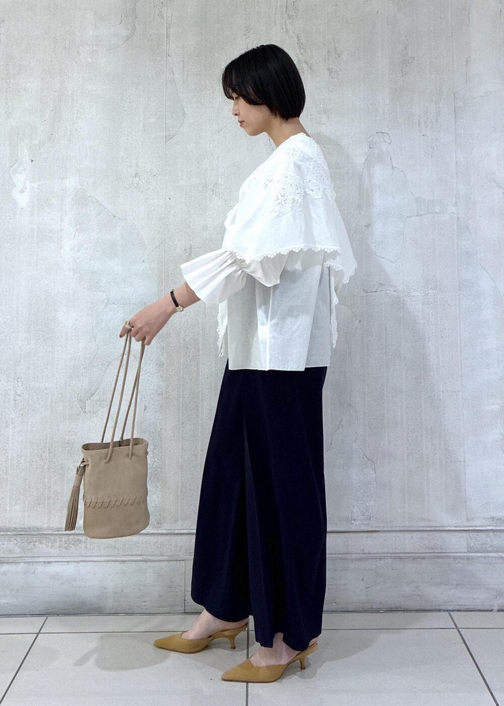 ベージュ系のショルダーバッグ、ホワイト系のシャツ/ブラウス、ブルー系のスラックスを着用したレディースの冬コーディネートの3枚目の写真