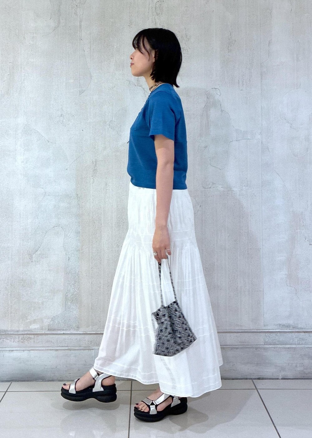 ホワイト系のスカート、ブラック系のトートバッグ、ブルー系のTシャツ/カットソーを着用したレディースの夏コーディネートの2枚目の写真