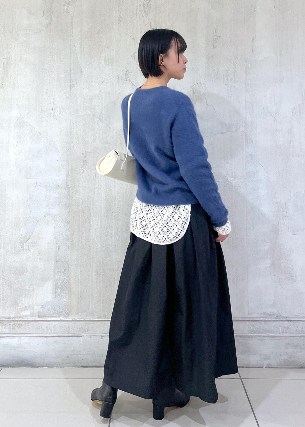 ホワイト系のショルダーバッグ、ブラック系のスカート、ホワイト系のTシャツ/カットソーを着用したレディースの冬コーディネートの3枚目の写真