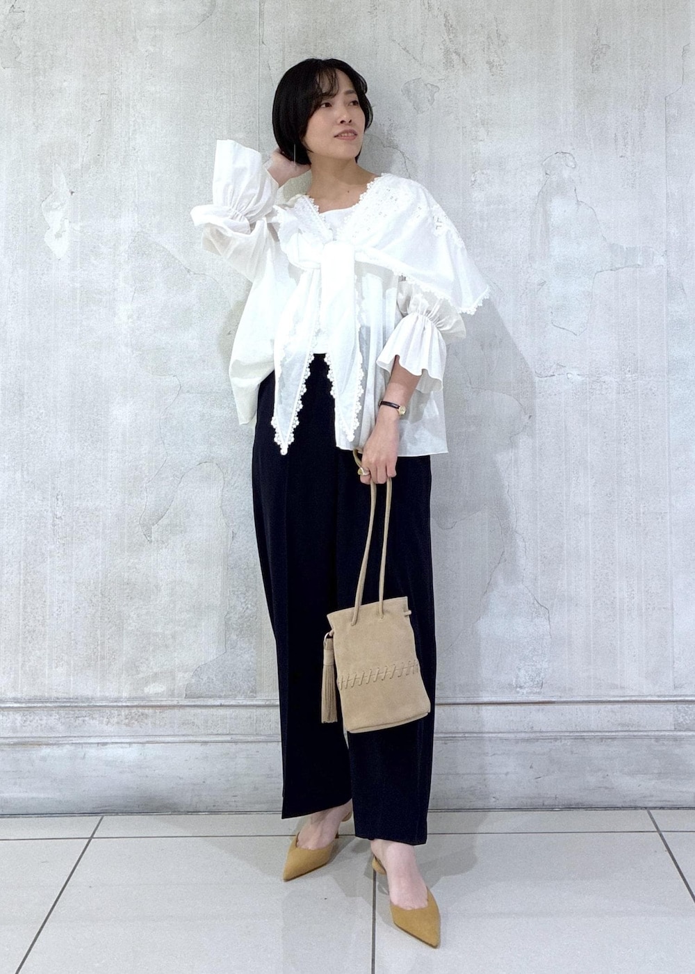 ベージュ系のショルダーバッグ、ホワイト系のシャツ/ブラウス、ブルー系のスラックスを着用したレディースの冬コーディネートの2枚目の写真