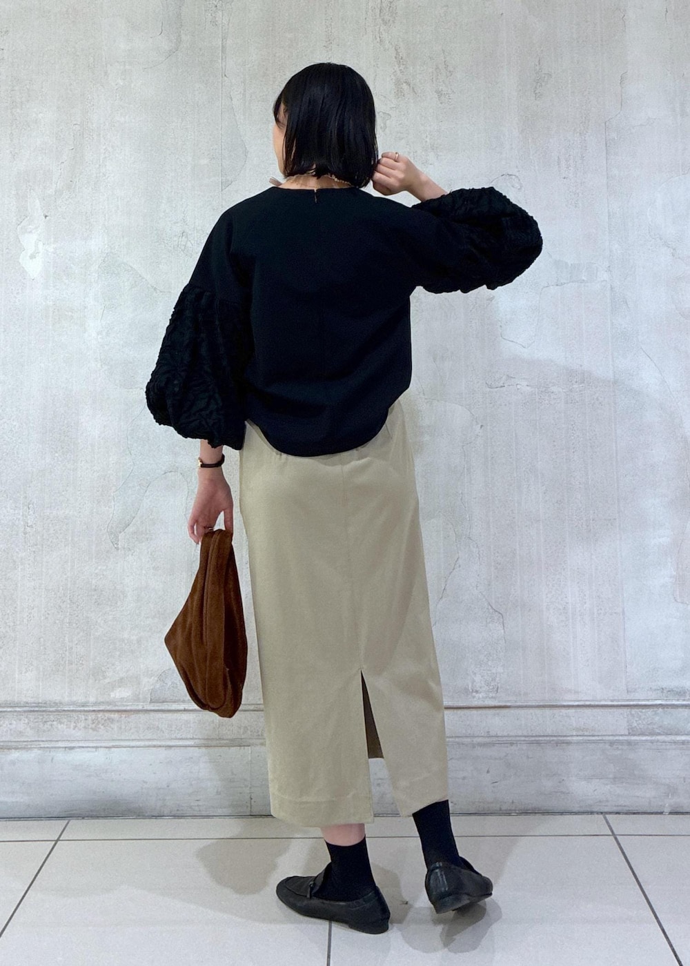 ブラウン系のハンドバッグ、ベージュ系のスカート、ブラック系のシャツ/ブラウスを着用したレディースの冬コーディネートの4枚目の写真