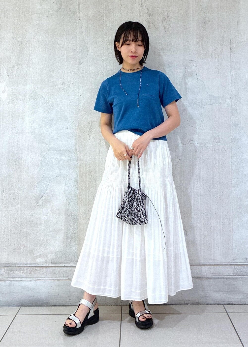 ホワイト系のスカート、ブラック系のトートバッグ、ブルー系のTシャツ/カットソーを着用したレディースの夏コーディネートの5枚目の写真