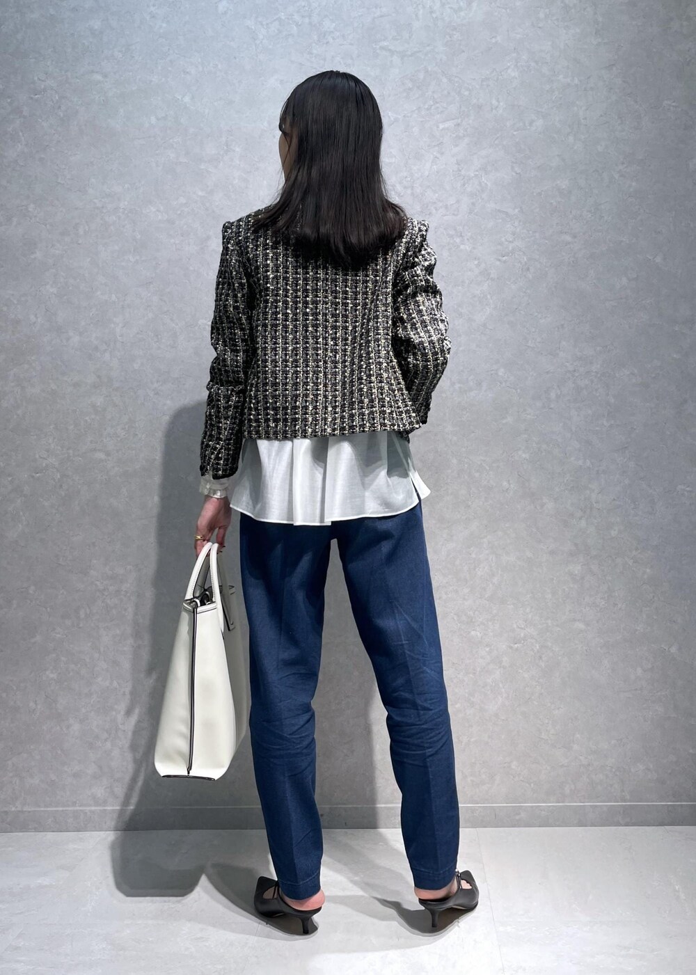 ブラック系のパンプス、ホワイト系のトートバッグ、ブルー系のデニムパンツを着用したレディースの秋コーディネートの3枚目の写真