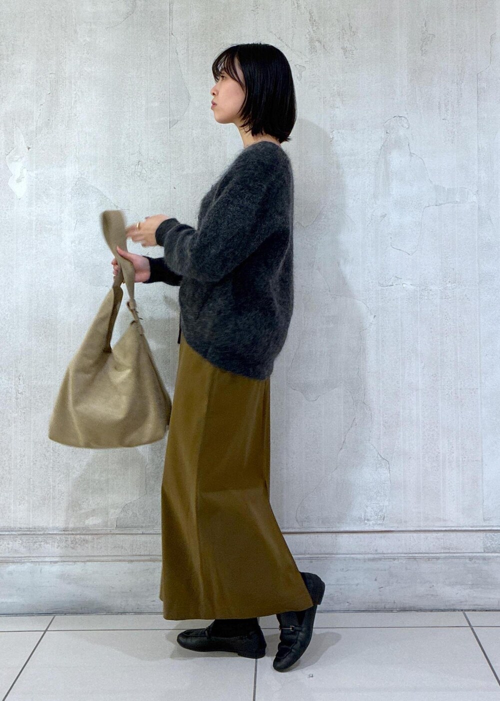 グレー系のカーディガン/ボレロ、ブラウン系のワンピース、ベージュ系のショルダーバッグを着用したレディースの冬コーディネートの3枚目の写真