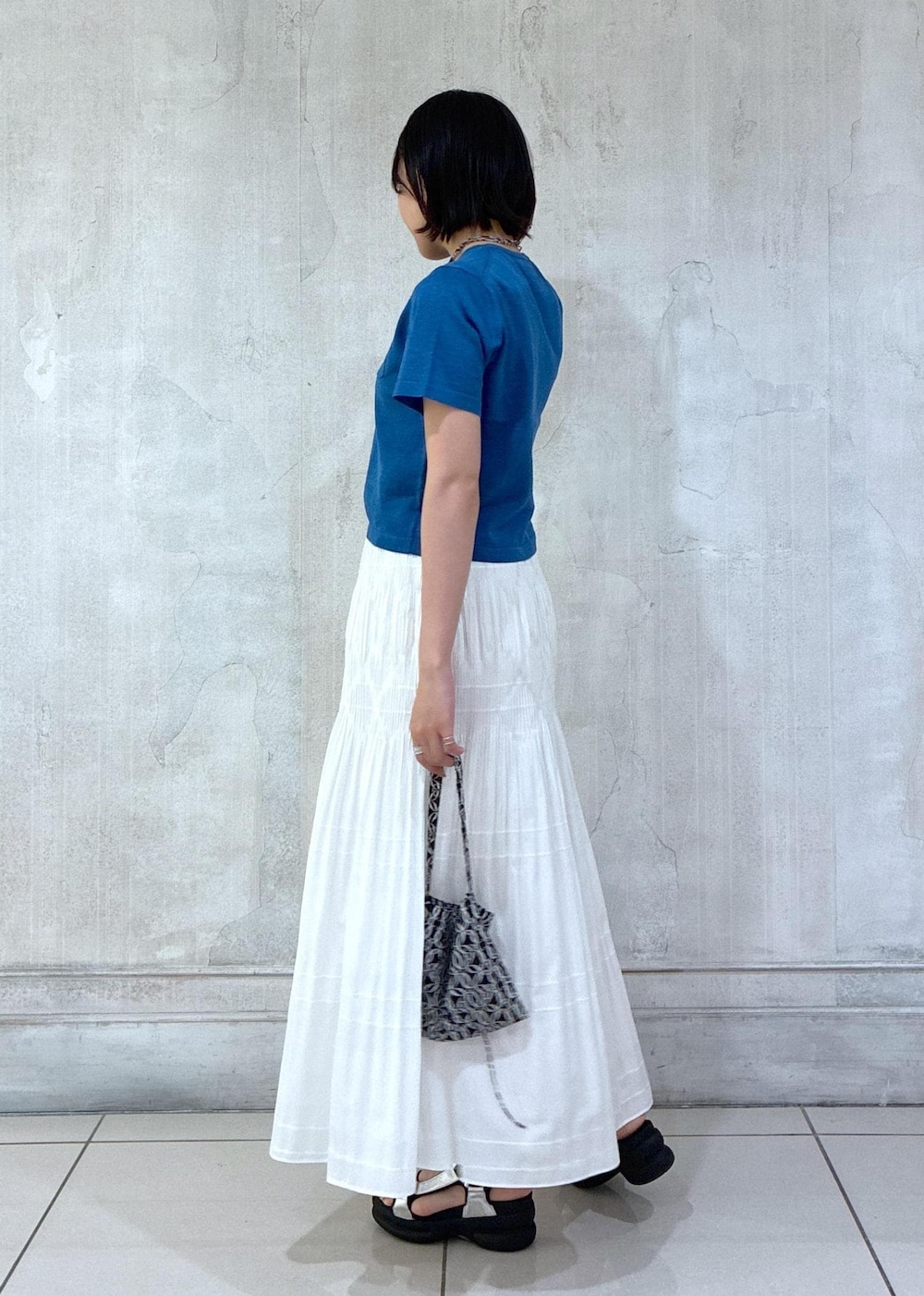 ホワイト系のスカート、ブラック系のトートバッグ、ブルー系のTシャツ/カットソーを着用したレディースの夏コーディネートの3枚目の写真