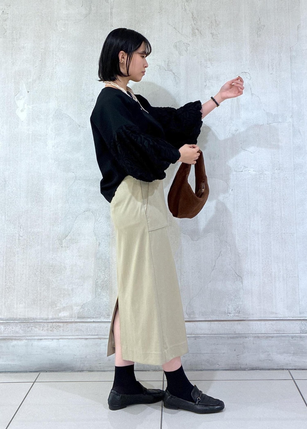 ブラウン系のハンドバッグ、ベージュ系のスカート、ブラック系のシャツ/ブラウスを着用したレディースの冬コーディネートの3枚目の写真